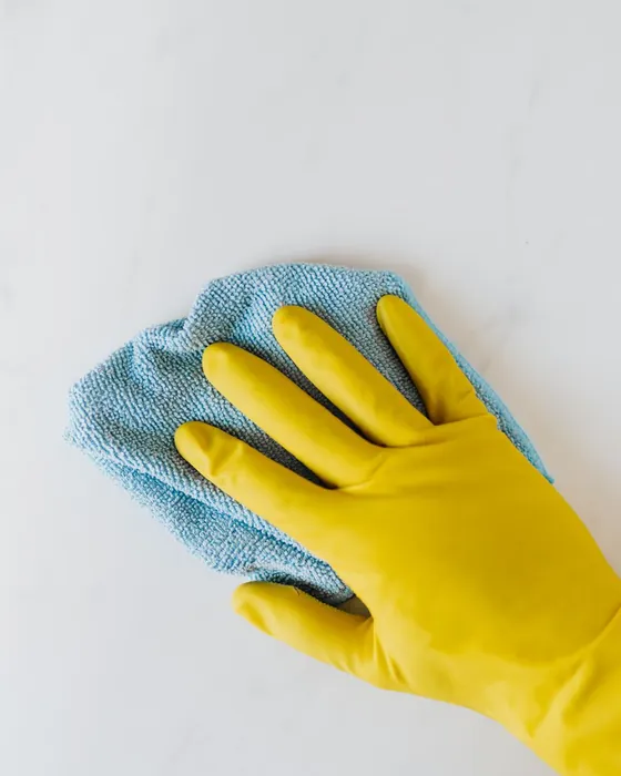 A gloved hand wiping a surface with a cloth