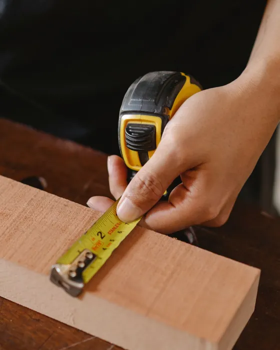 A tape measure held against a plank of wood