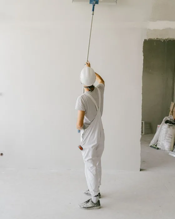 A painter rolling a wall in white overalls